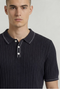 Front image of a model wearing the Deep river button knit polo in black, by brand Deep