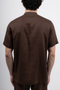 Back image of a model wearing the Deep strike linen shirt in brown, by brand Deep