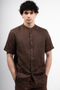 Front image of a model wearing the Deep strike linen shirt in brown, by brand Deep