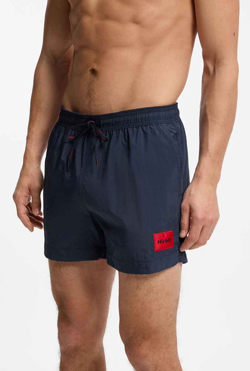 Front image of a model wearing Dominica swimshorts in navy, by brand Hugo
