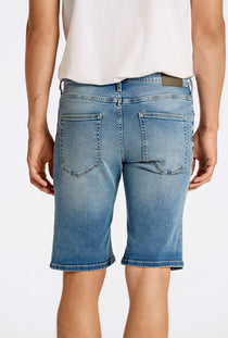Back image of a model wearing the Superflex denim shorts in dark denim, by brand Lindbergh