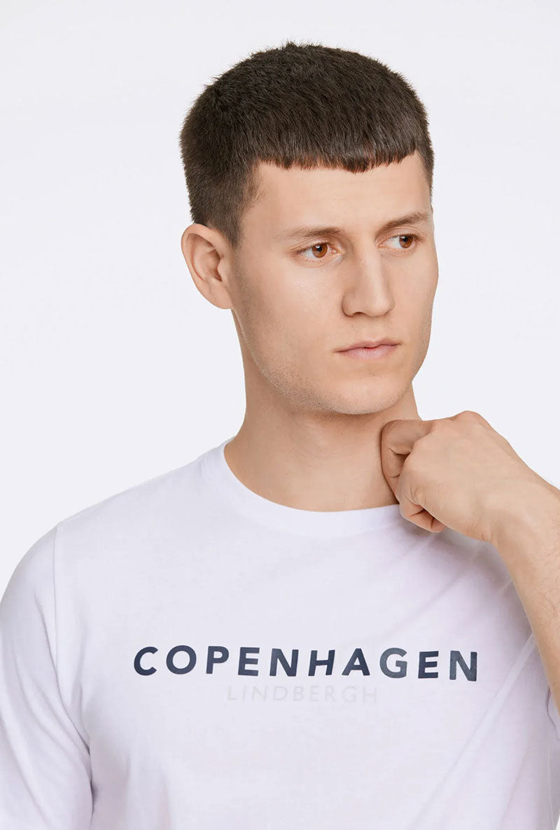 Front image of a model wearing Lindbergh logo print ss tshirt in white, by brand Lindbergh