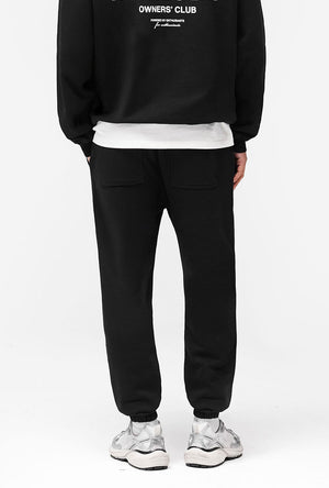 Back image of a model wearing the Owners club sweatpant in black, by brand Represent