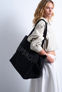 Front image of a model wearing the Ivy tote bag in black, by brand Top shop