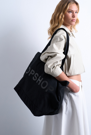 Front image of a model wearing the Ivy tote bag in black, by brand Top shop