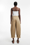 Back image of a model wearing the Noor high rise cargo trousers in tan, by brand Top shop