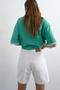 Back image of a model wearing the Vigga high rise white denim shorts in white, by brand Top shop