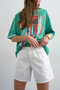 Front detail image of a model wearing the Vigga high rise white denim shorts in white, by brand Top shop