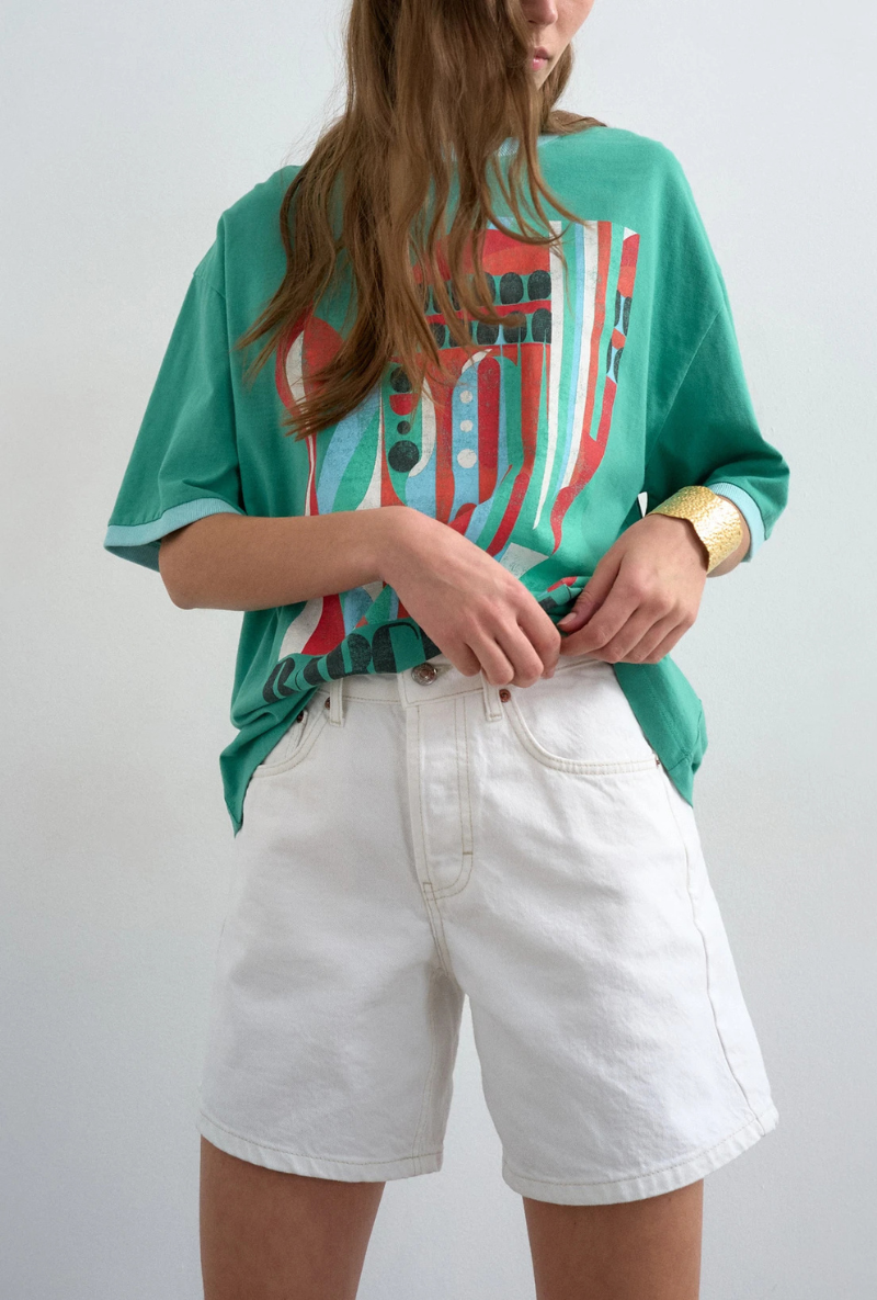 Front detail image of a model wearing Vigga high rise white denim shorts in white, by brand Top shop
