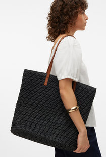 Side image of a model wearing the Vero moda sisso beach bag in black, by brand Vero moda