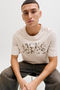 Front image of a model wearing the Jack and jones jeff logo tee in stone, by brand Jack&jones