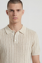 Front image of a model wearing the Deep river button knit polo in beige, by brand Deep