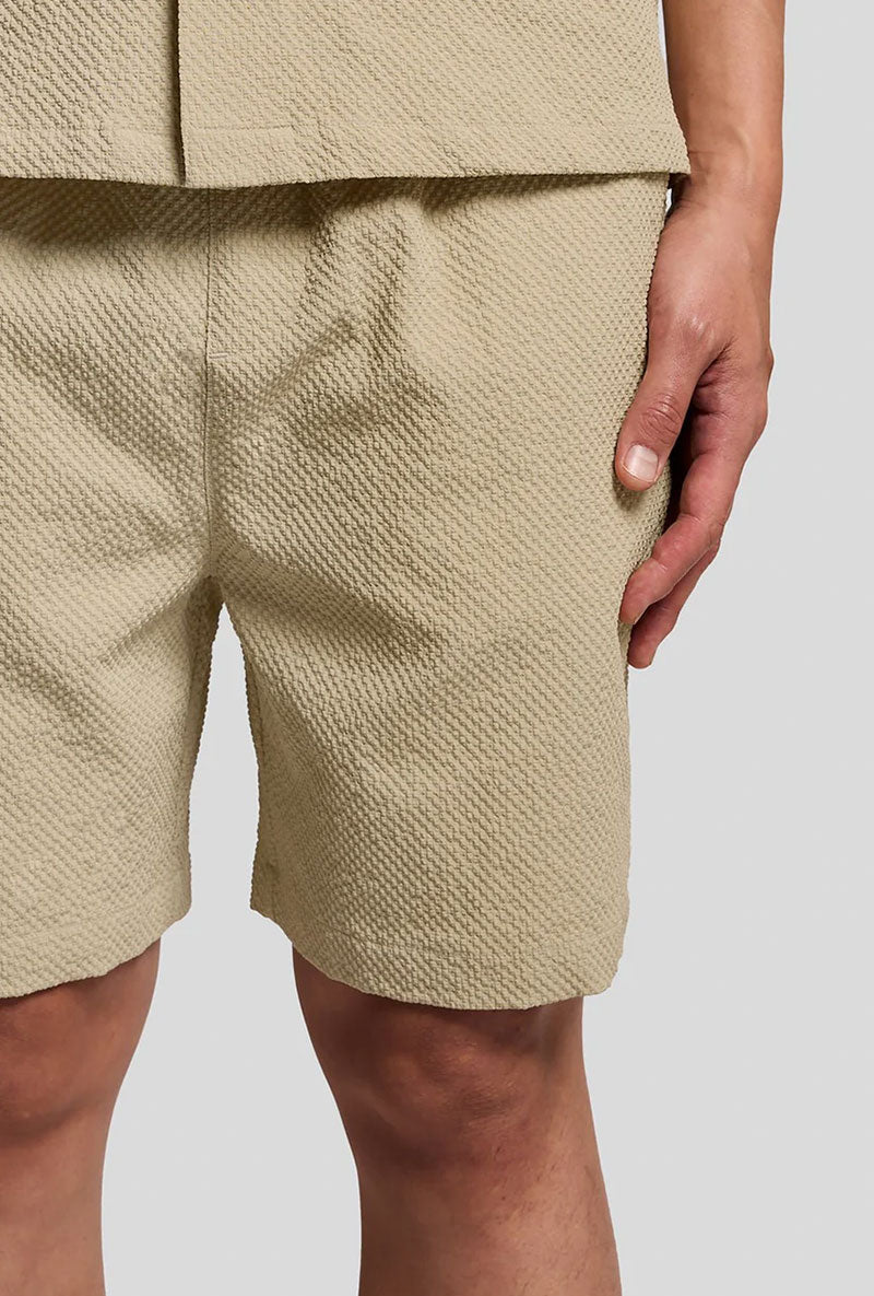 Front image of a model wearing Crinkle resort shorts in stone, by brand Lyle and scott