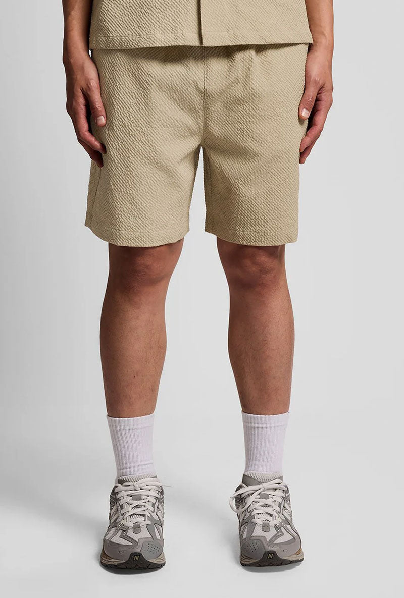 Front image of a model wearing Crinkle resort shorts in stone, by brand Lyle and scott