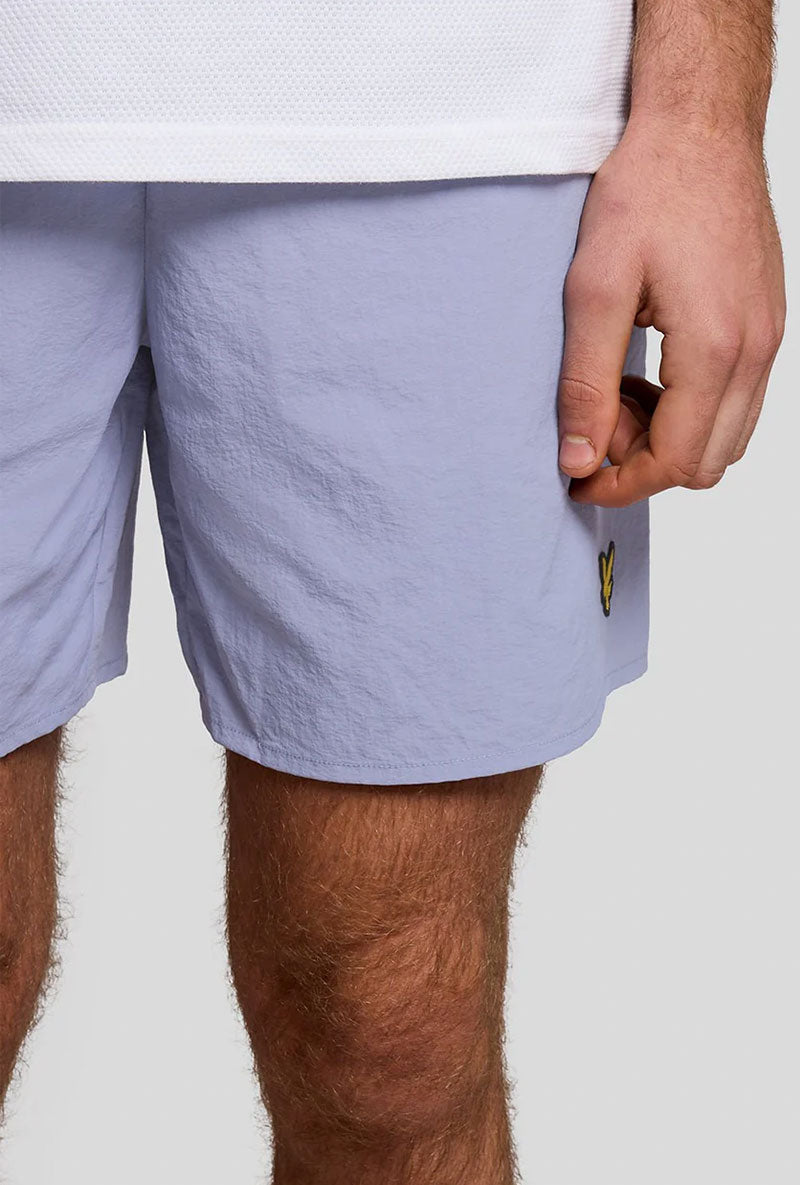 Front detail image of a model wearing Plain swimshorts in blue, by brand Lyle and scott