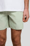 Front detail image of a model wearing the Plain swimshorts in sage, by brand Lyle and scott