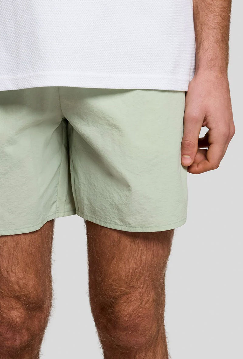 Front detail image of a model wearing Plain swimshorts in sage, by brand Lyle and scott