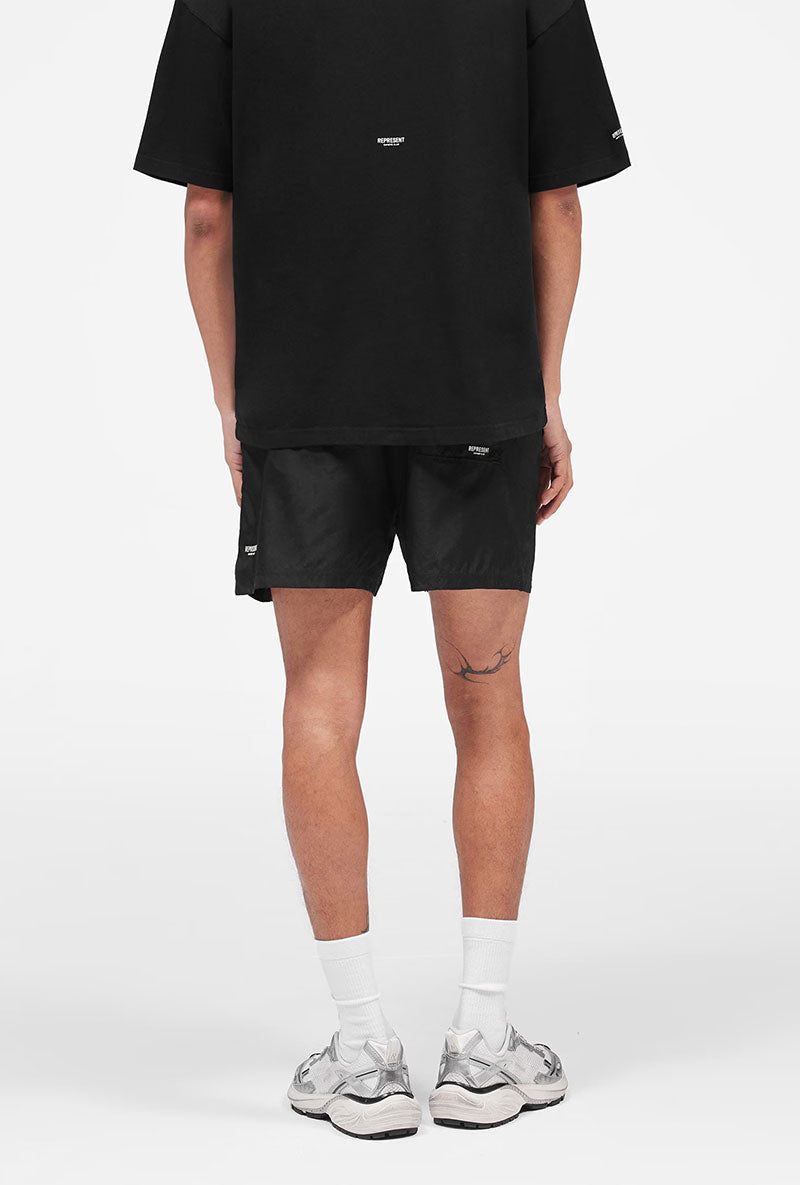 Back image of a model wearing Micro owners club swimshorts in black, by brand Represent