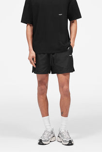 Front image of a model wearing the Micro owners club swimshorts in black, by brand Represent