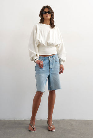 Front image of a model wearing the Rega cinch waist sweatshirt in off white, by brand Top shop
